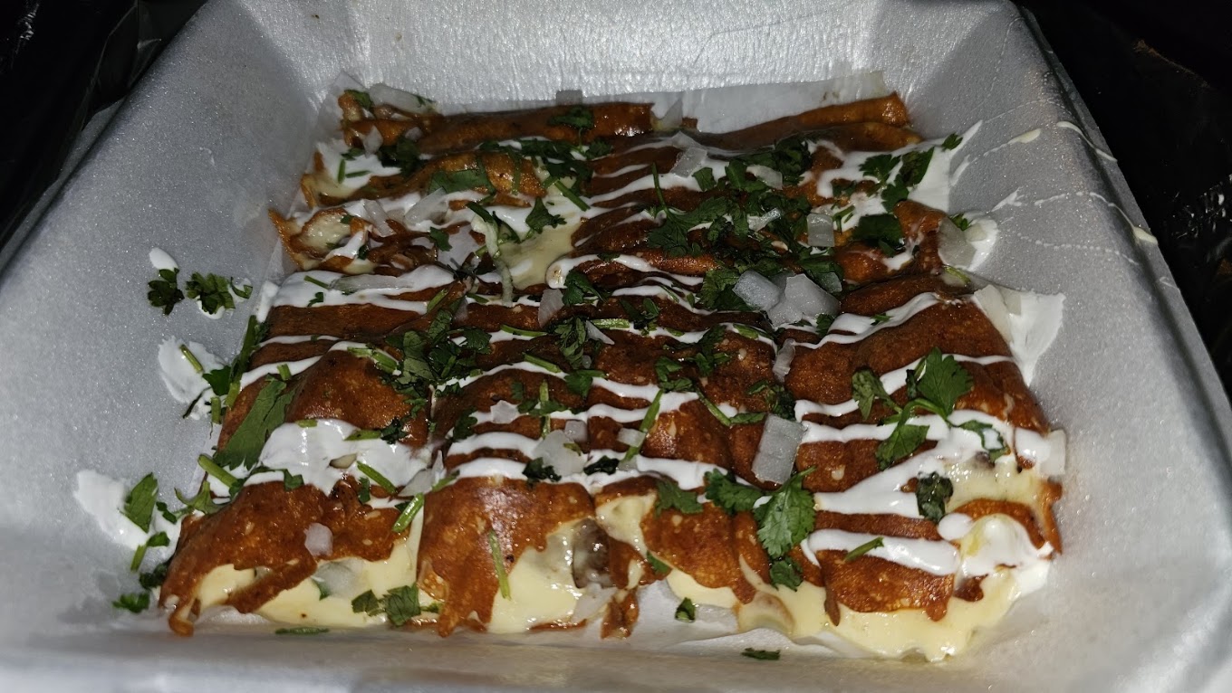 Enchiladas smothered in red sauce with crema, onion and cilantro