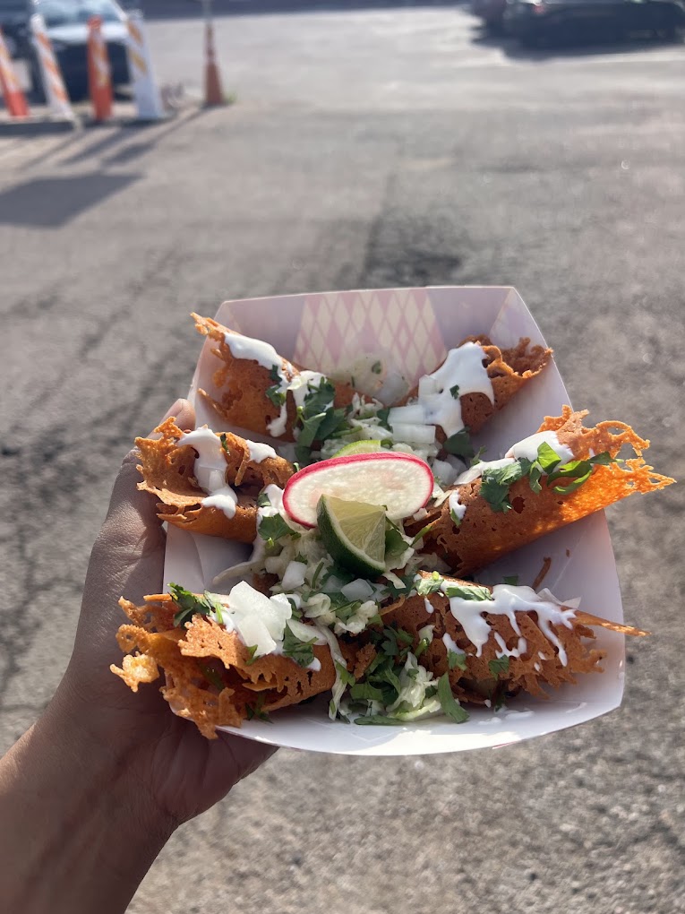 Crispy cheese-crusted tacos with slaw, radish and lime held in a paper tray