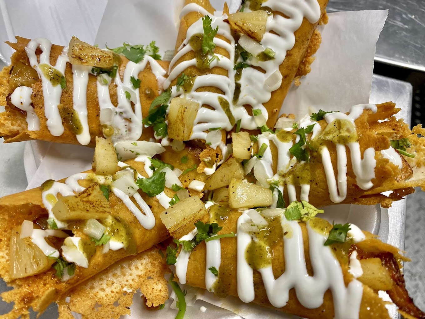Crispy cheese-wrapped flautas drizzled with crema and salsa verde