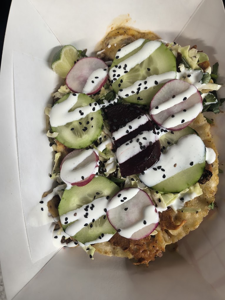 Fried tostada topped with cucumber, radish, beets and crema