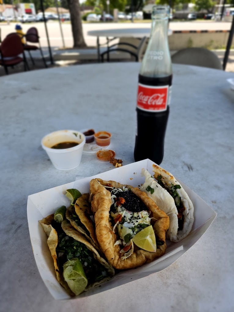 Tray of assorted tacos and gorditas with lime and soup